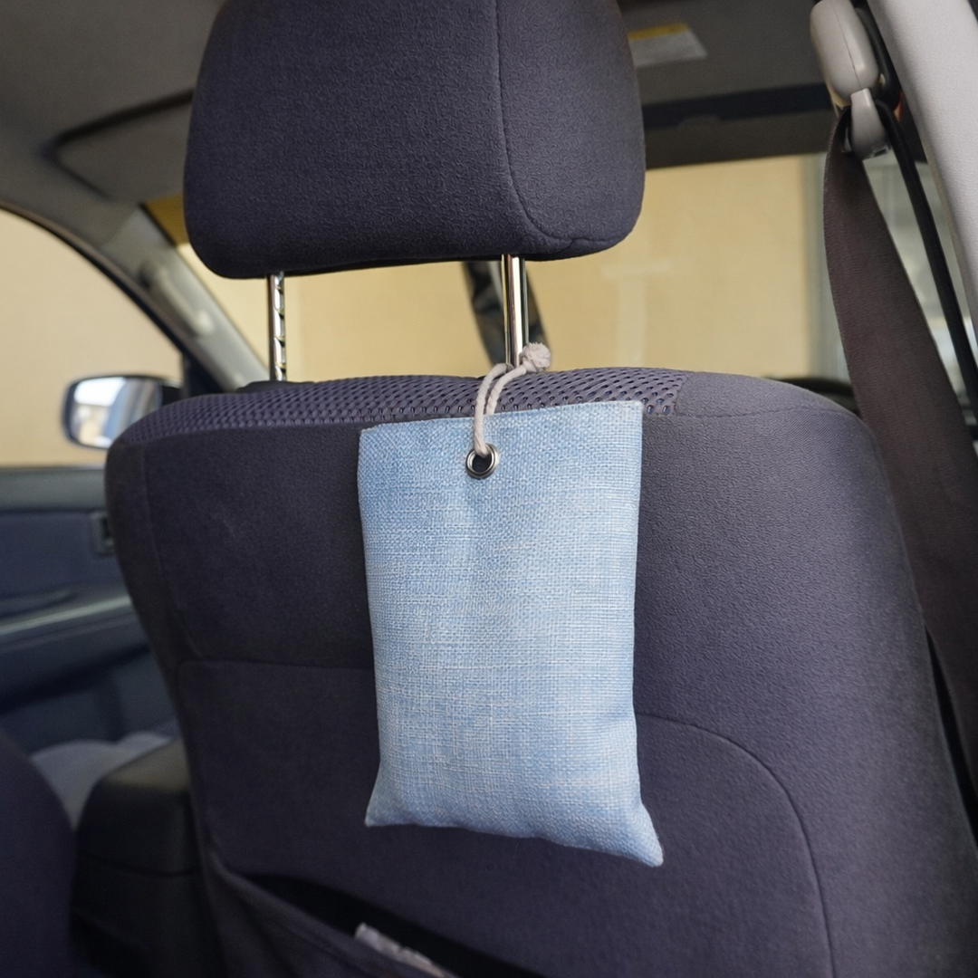Blue fabric Activated charcoal moisture absorber hanging from car headrest to remove wet dog smells and moisture.