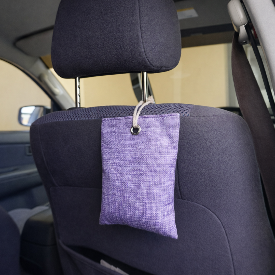 Purple charcoal moisture and odour absorber hanging from a car's headrest.